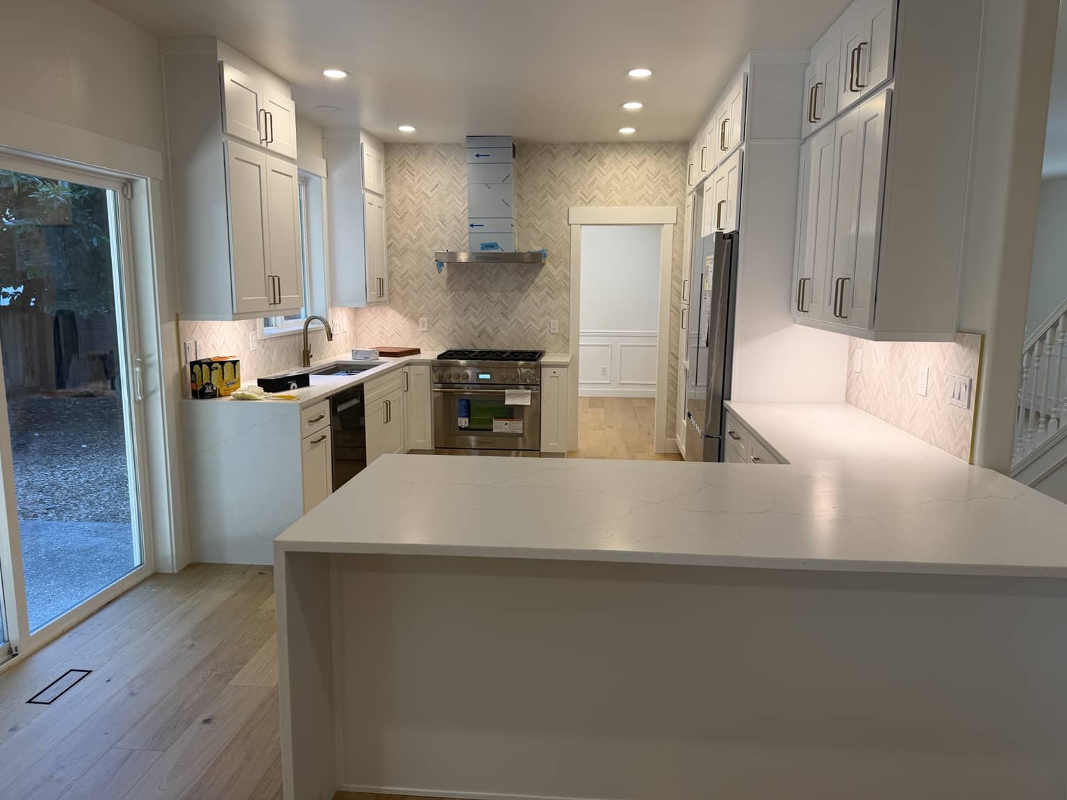 Completed North Seattle kitchen remodel by Pars WA Construction with white cabinets, quartz countertops, tile backsplash and a large island