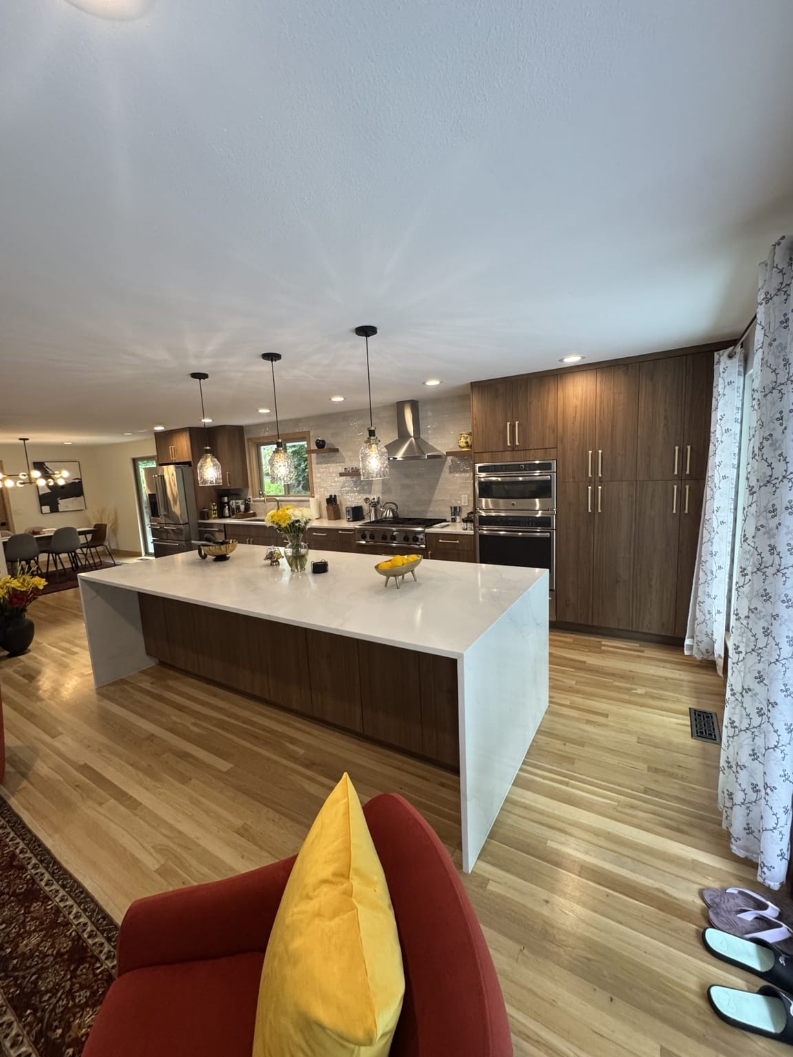 Completed open-concept Kirkland kitchen remodel with flat-panel cabinets, quartz waterfall island, new flooring and lighting